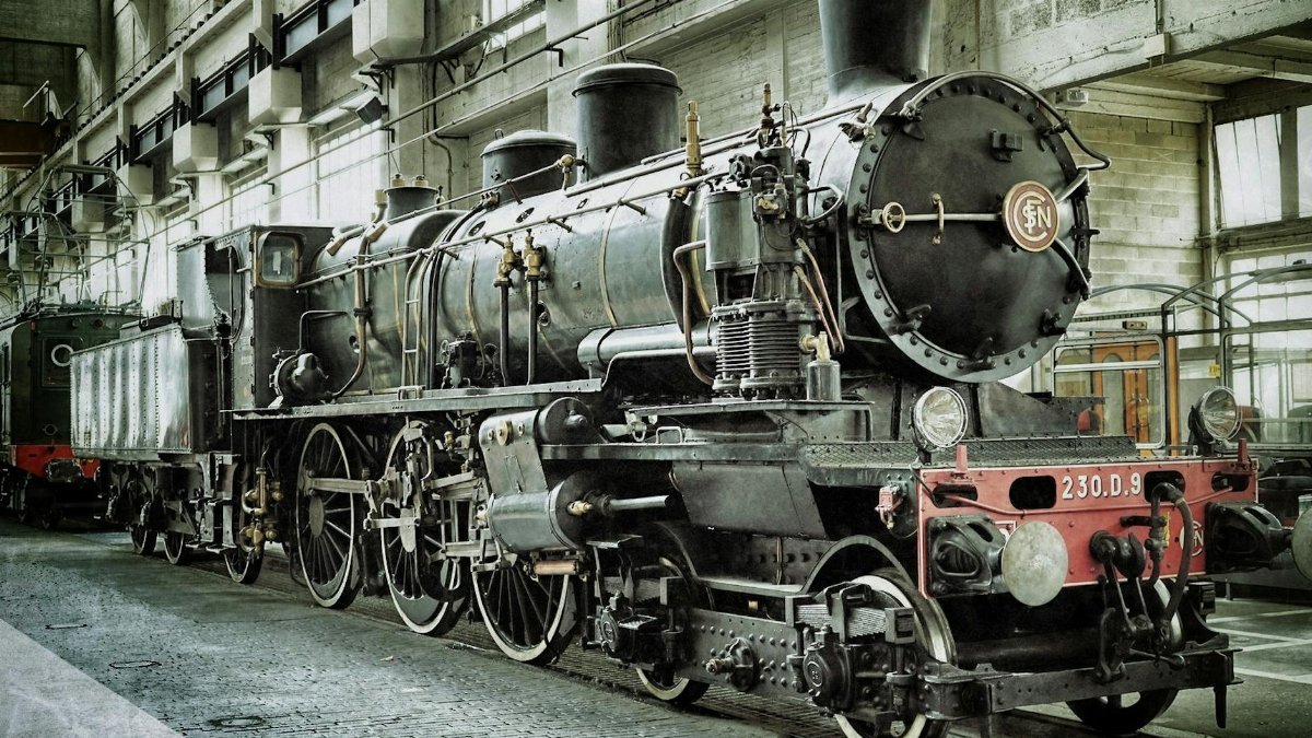 A detailed view of a vintage steam locomotive in an indoor railway station.