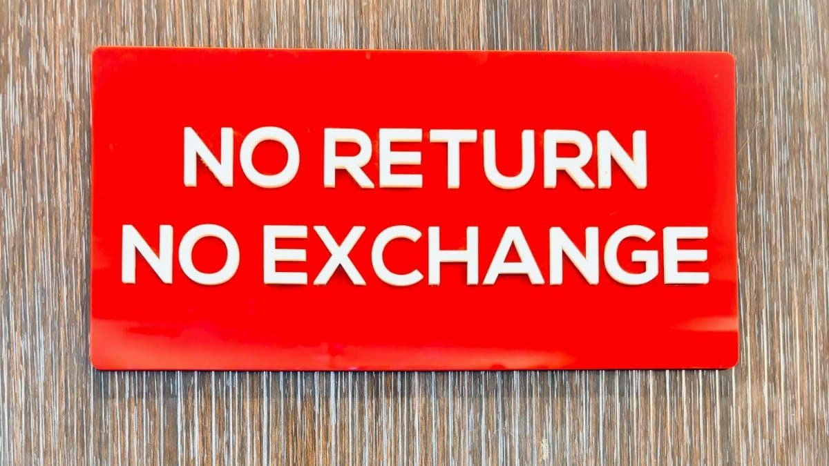 Bold red sign with 'No Return No Exchange' message on a wooden backdrop.