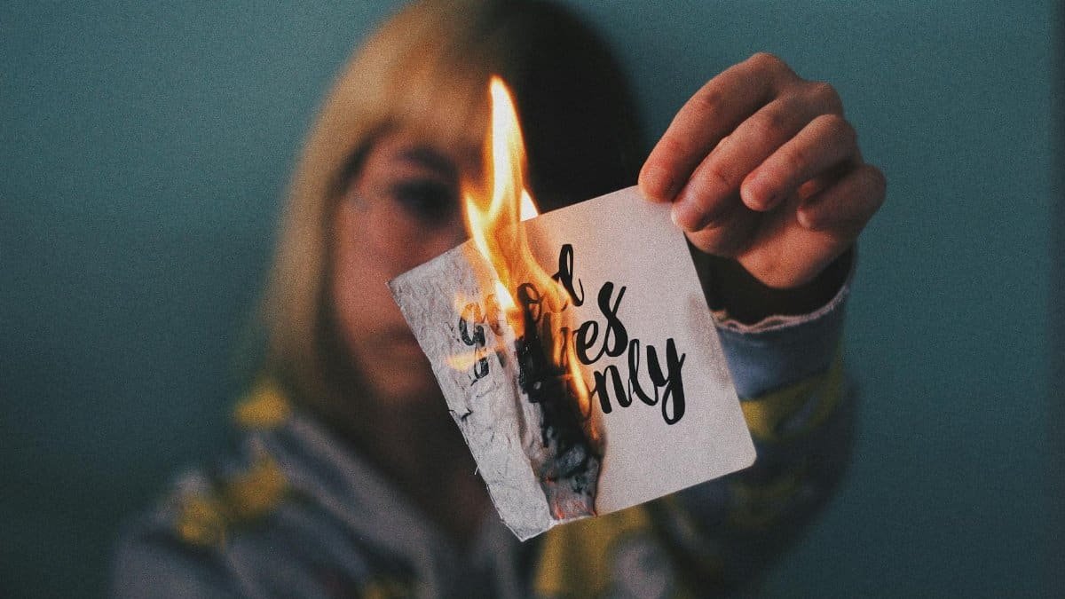 A woman holds a burning paper with text, capturing a moment of transformation and energy.