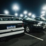 Rows of illuminated cars in a parking lot at night, showcasing a peaceful, urban atmosphere.