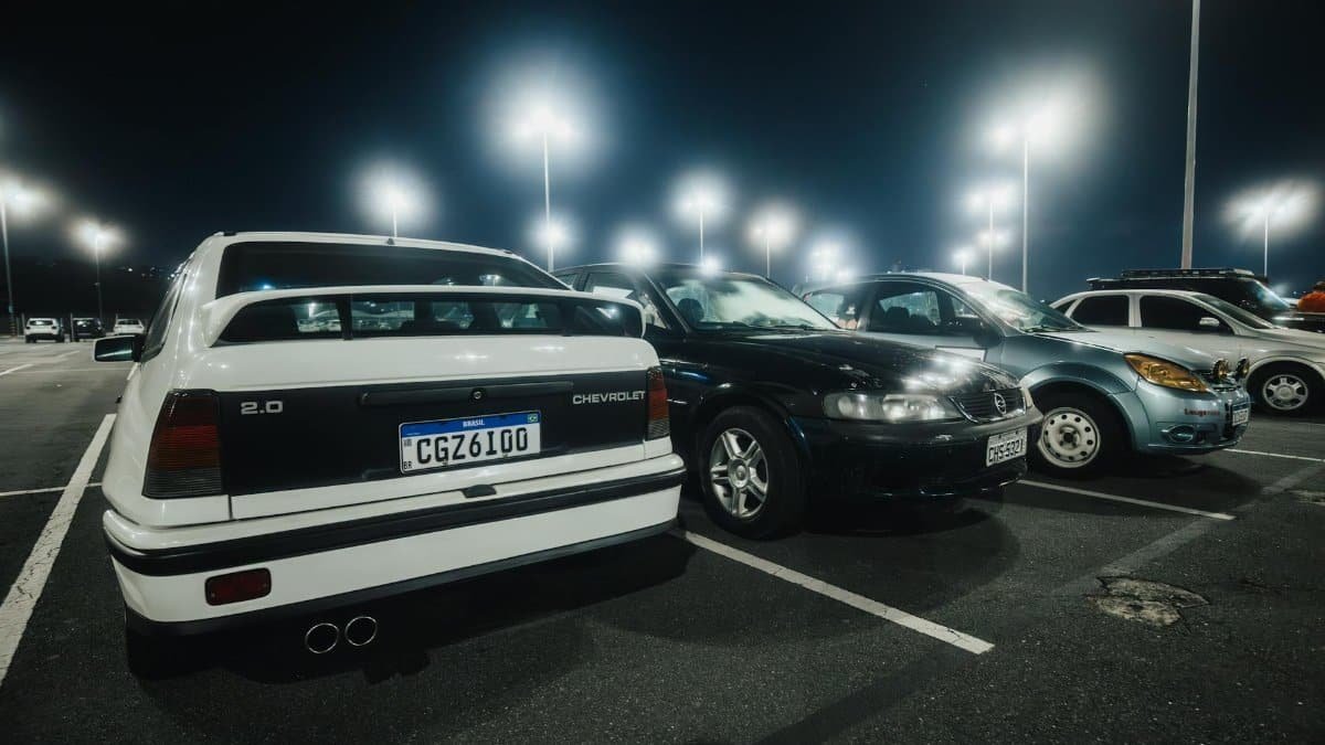 Rows of illuminated cars in a parking lot at night, showcasing a peaceful, urban atmosphere.