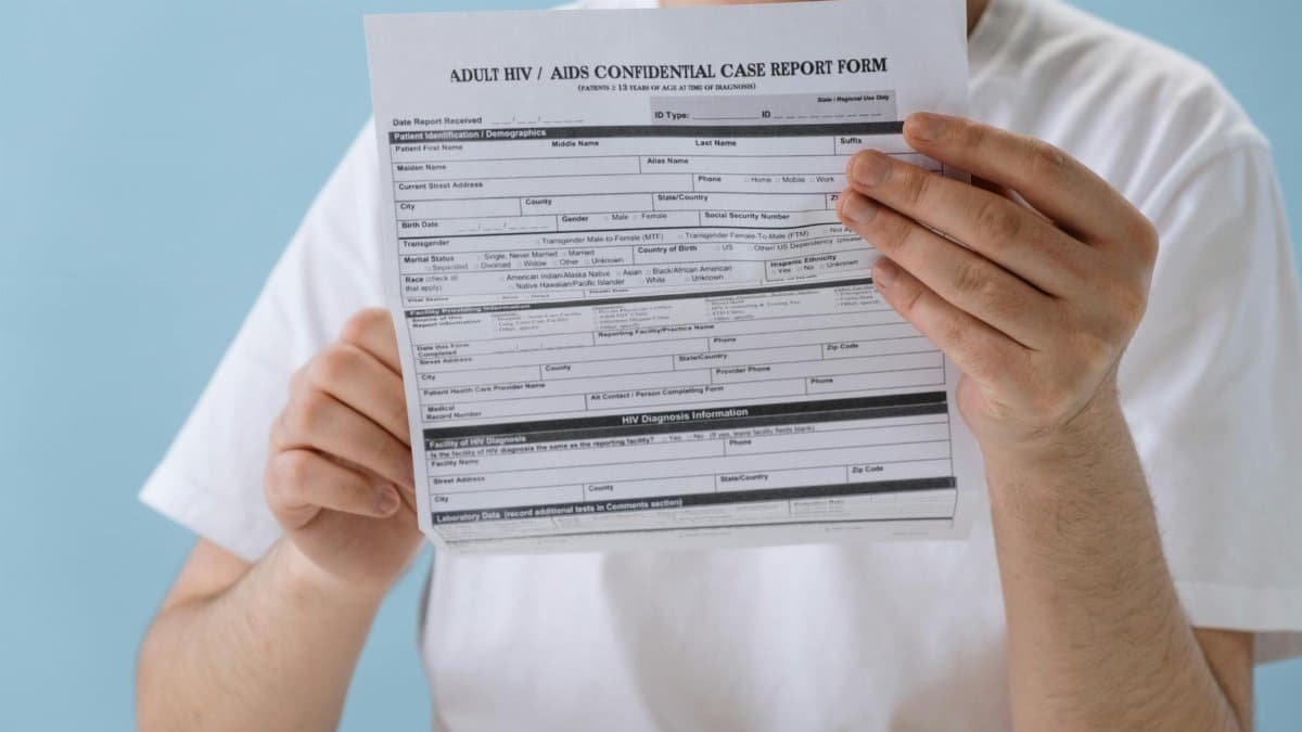 Person holding confidential HIV/AIDS case report form, symbolizing health awareness and privacy.