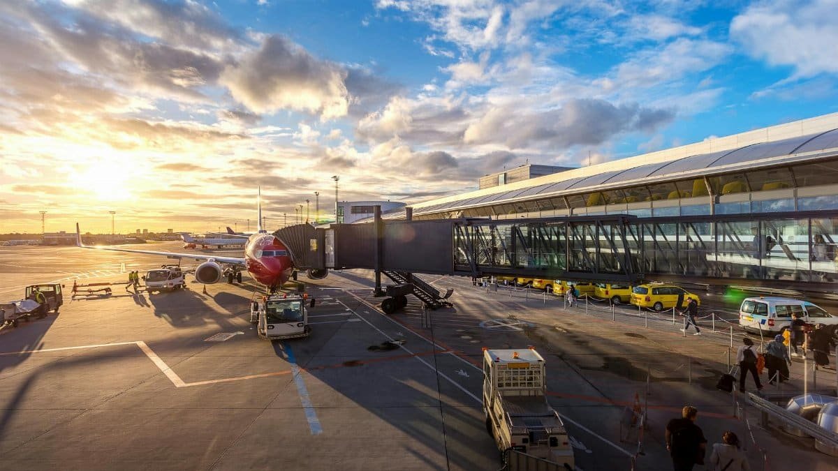 A vibrant sunset at Copenhagen Airport with airplanes and bustling activity.