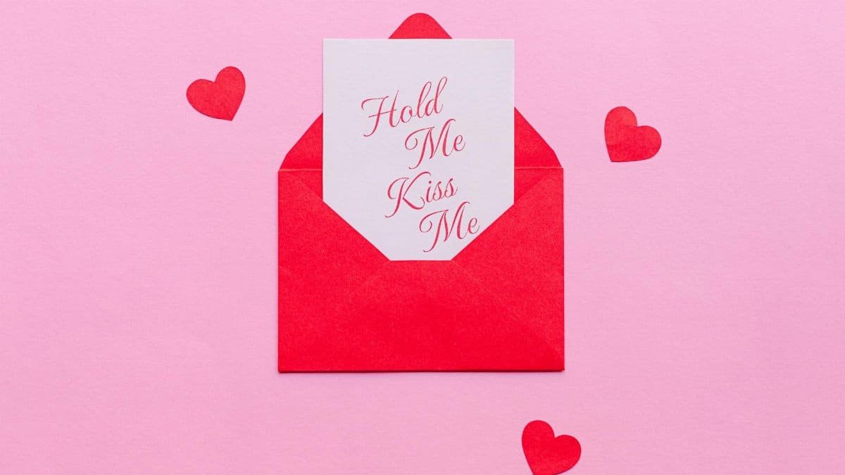 Red envelope with romantic card on a pink background, perfect for Valentine's Day.
