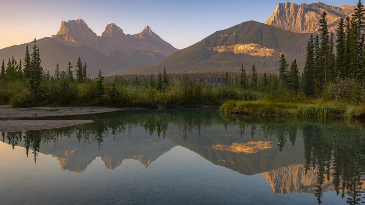 Breathtaking sunrise reflection of Three Sisters mountains at Canmore, Alberta, Canada.