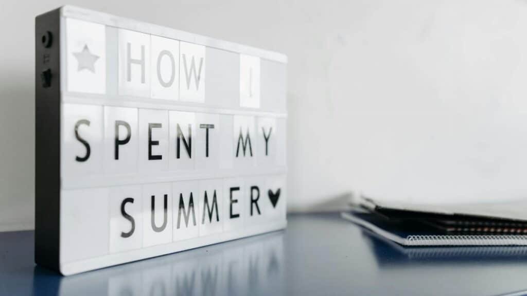 Close-up of a lightbox with 'How I Spent My Summer' text on a desk.