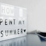 Close-up of a lightbox with 'How I Spent My Summer' text on a desk.