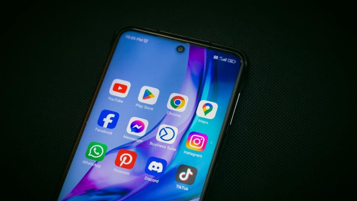 Close-up of a smartphone screen showing popular app icons like YouTube, Maps, and TikTok on a black background.