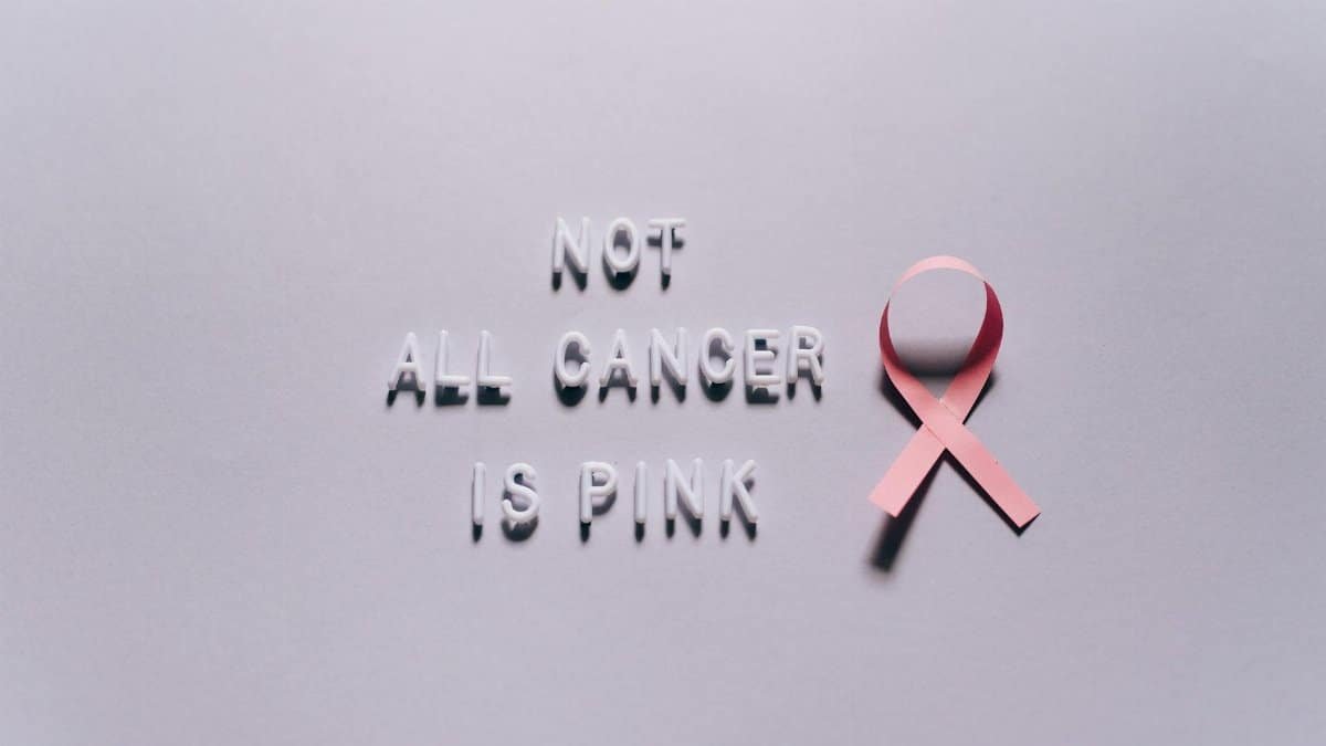 Pink ribbon highlighting diverse cancer awareness on a white surface.