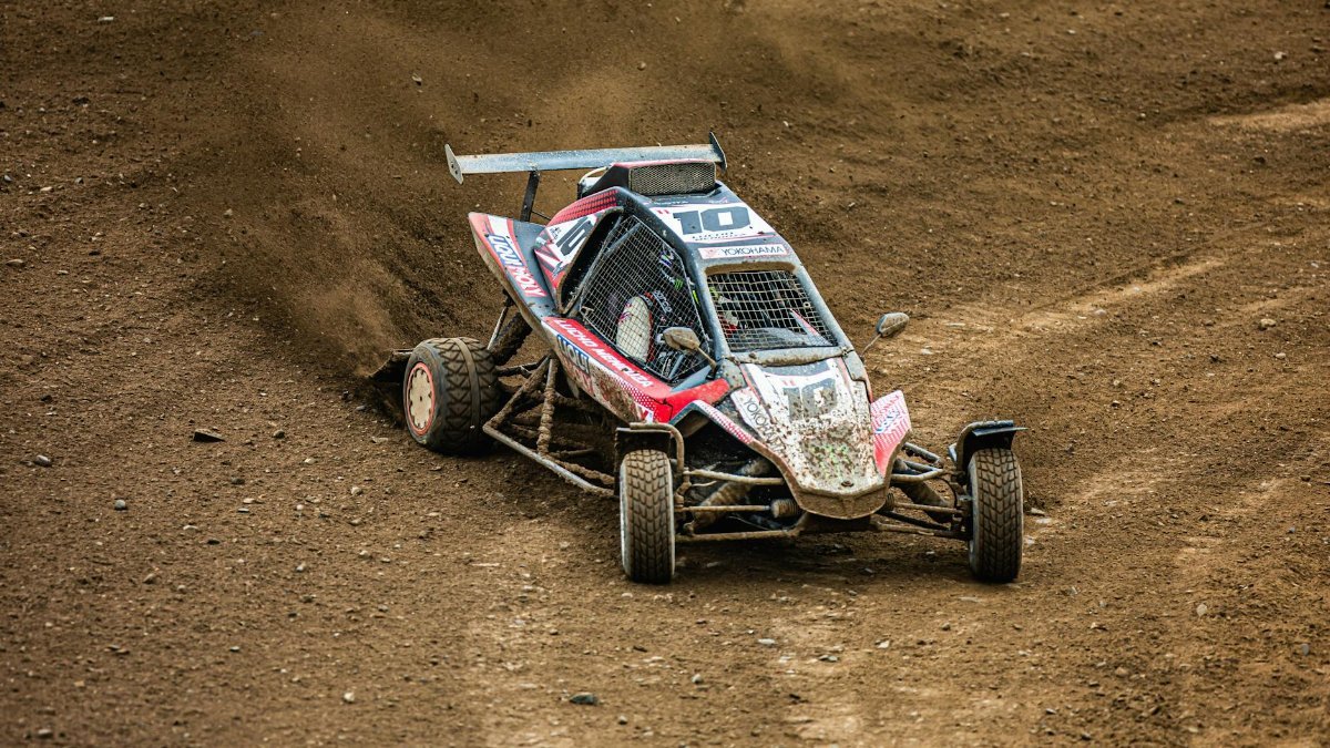 High-speed off-road buggy kicking up dust on a dirt track.