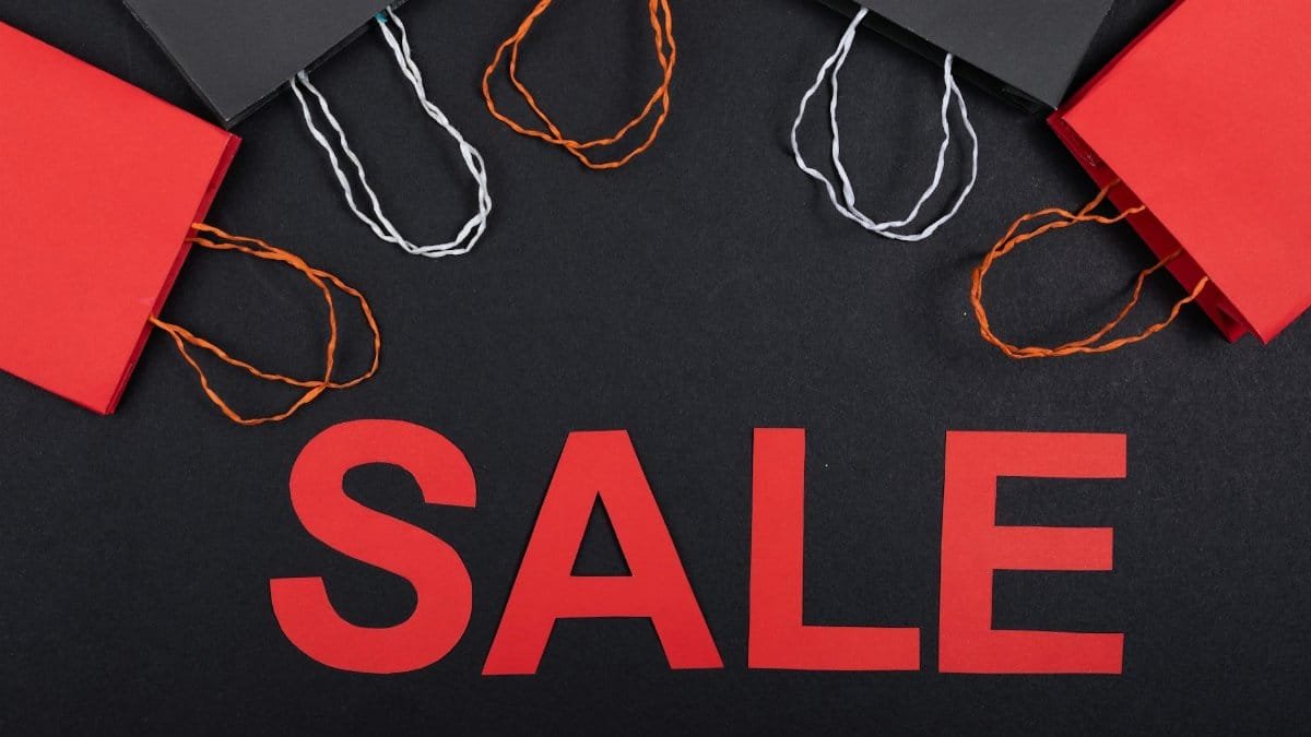 Top view of red and black shopping bags with sale text on a black background.