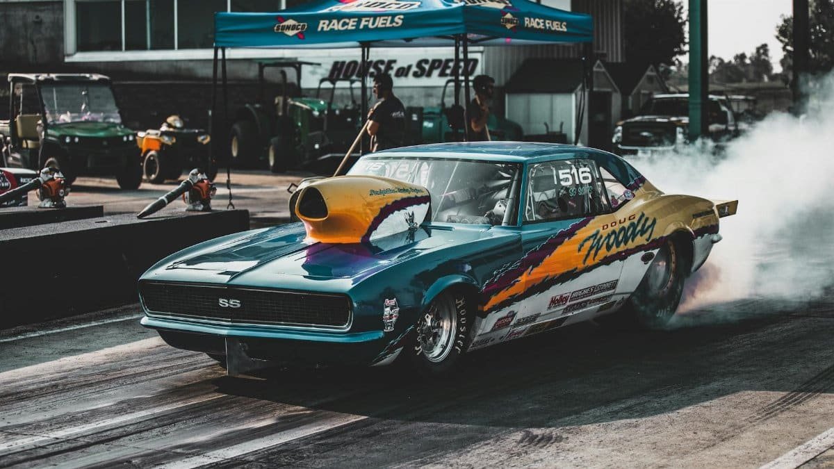 Retro sports car revving up for a race at Topeka drag strip, showcasing power and speed.