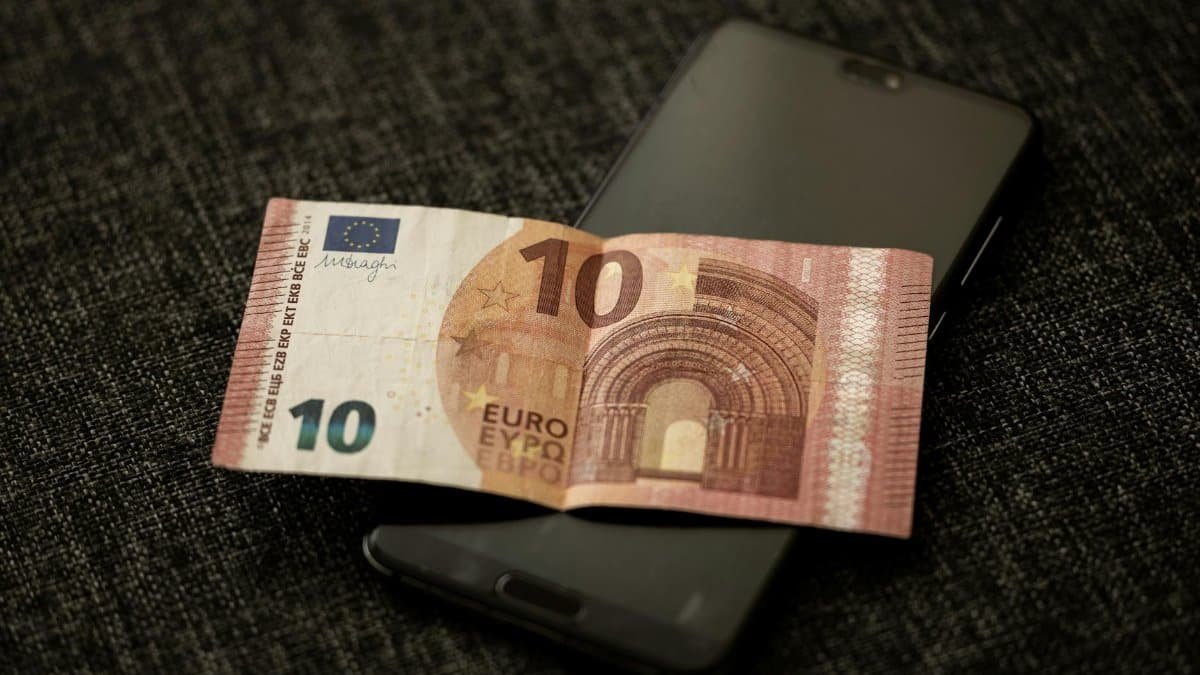A close-up shot of a 10 euro banknote placed on a smartphone, highlighting currency and digital technology.