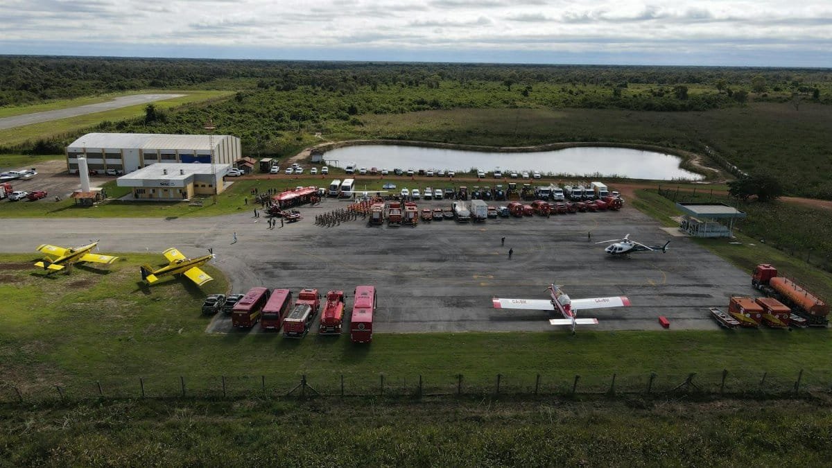 Aerial view of a firefighting base with planes, fire trucks, and emergency personnel ready for action.