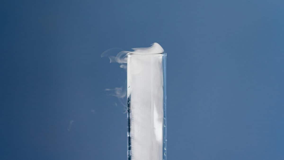 A scientific experiment with a test tube emitting vapor, set against a calming blue background.