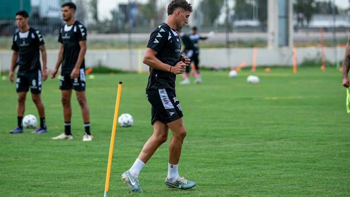 Soccer players training outdoors on a green field, focusing on drills and teamwork.