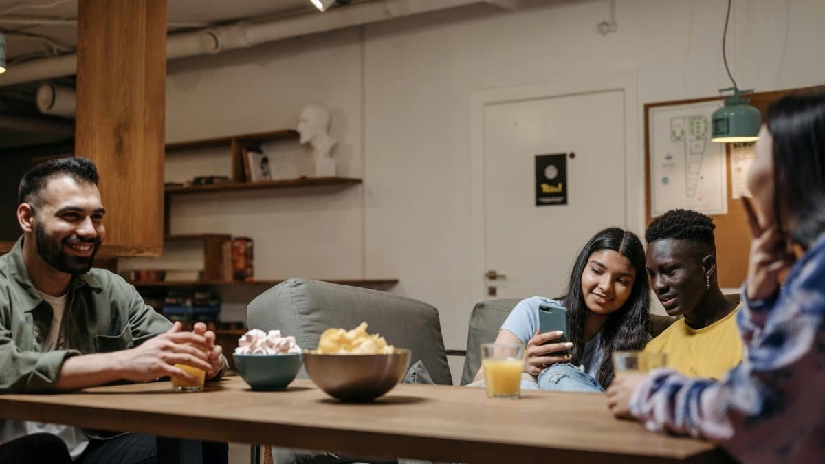 A diverse group of friends sitting together enjoying snacks and drinks indoors, capturing a moment of relaxation and bonding.