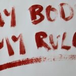 Bold empowerment statement 'My Body My Rules' in red paint on white background.