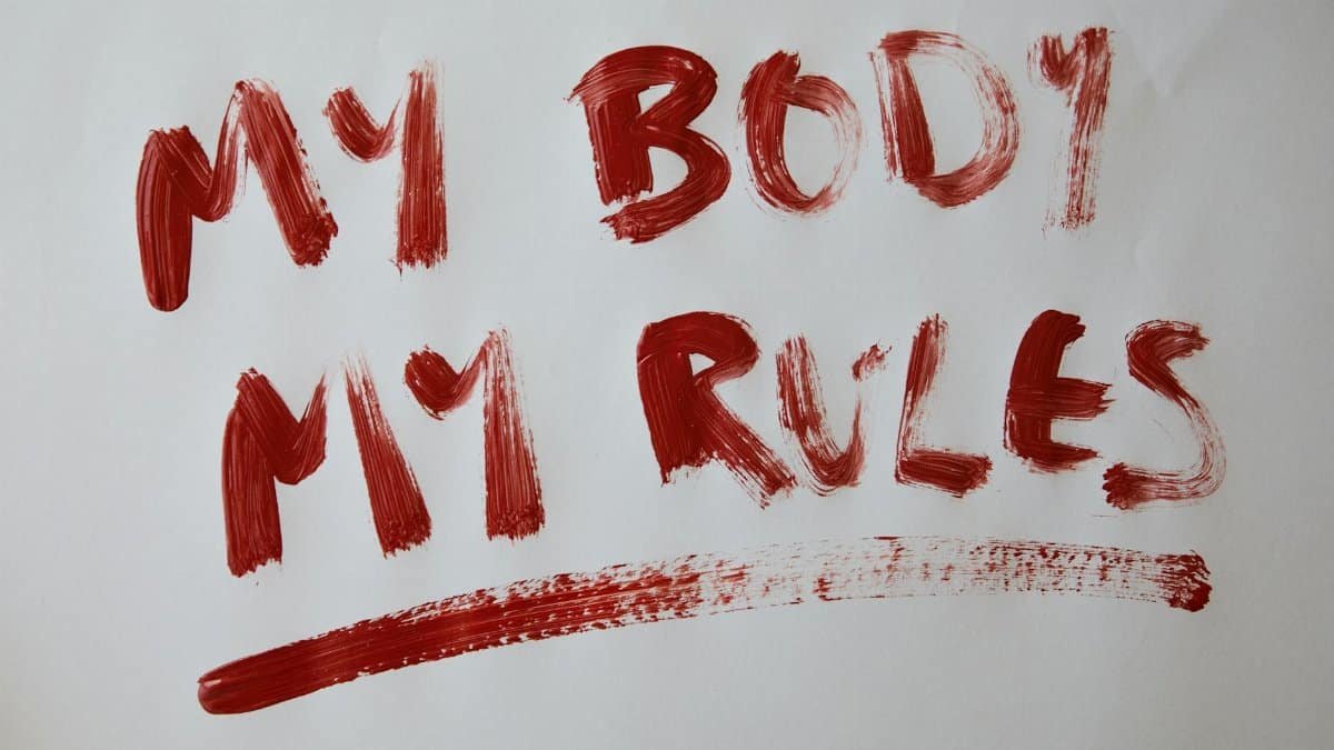 Bold empowerment statement 'My Body My Rules' in red paint on white background.