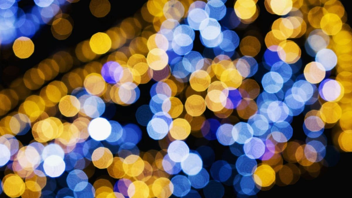 Vibrant blue and gold bokeh lights create a stunning abstract pattern on a black background.