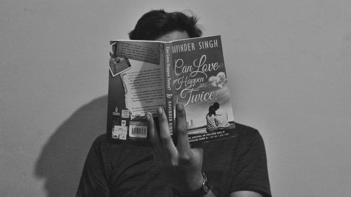 A young man reads 'Can Love Happen Twice?' in a black and white portrait.