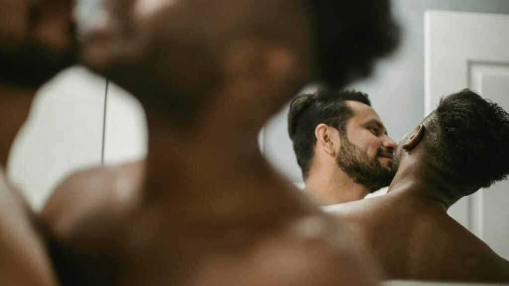 A romantic and intimate moment shared by a shirtless couple in a mirror reflection.