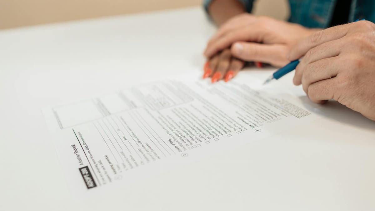 Close-up of hands signing adoption papers in an office environment, symbolizing family and legal process.