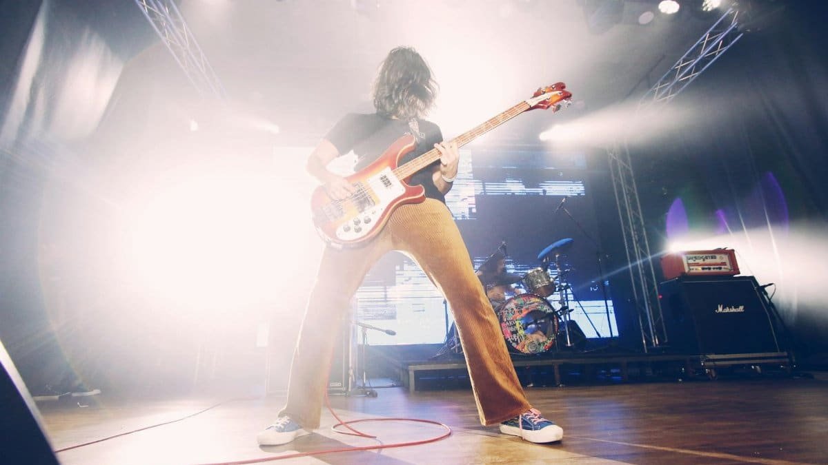 Dynamic low angle shot of a guitarist performing live on stage with vibrant lighting effects.