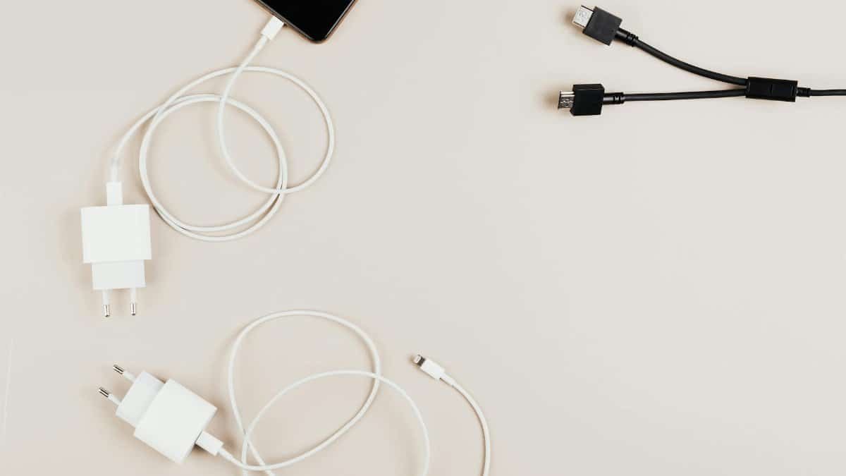 Flat lay of mobile devices with chargers and cables on a neutral background.