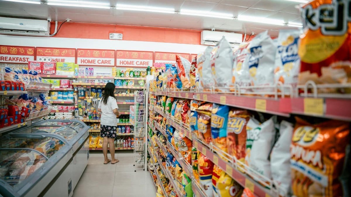 A woman browsing snack shelves at a supermarket, surrounded by various chips packages.