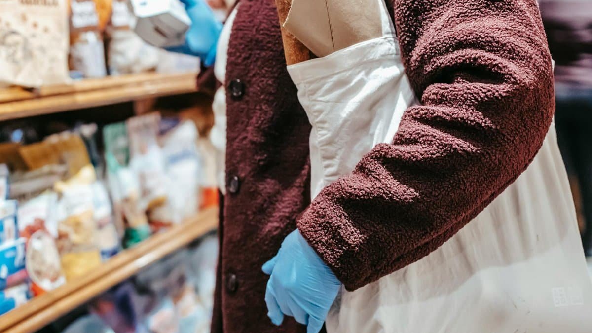 Anonymous woman shopping with a reusable bag in a grocery store, emphasizing sustainability.