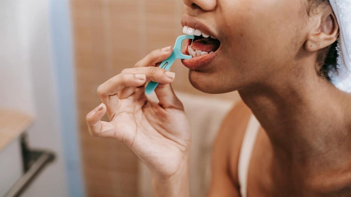 Close-up of a woman using a dental floss pick, promoting oral hygiene and daily care.
