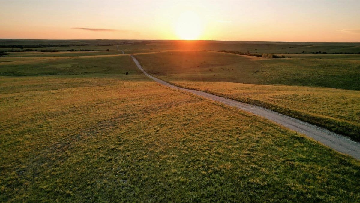 A serene sunset over rural fields with a winding dirt road in Eureka, Kansas.