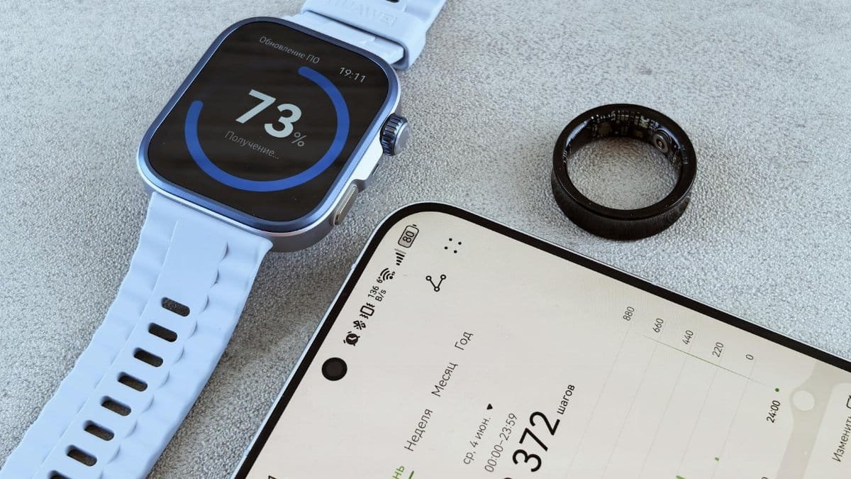 Smartwatch with fitness data, smartphone, and health ring on a gray surface.
