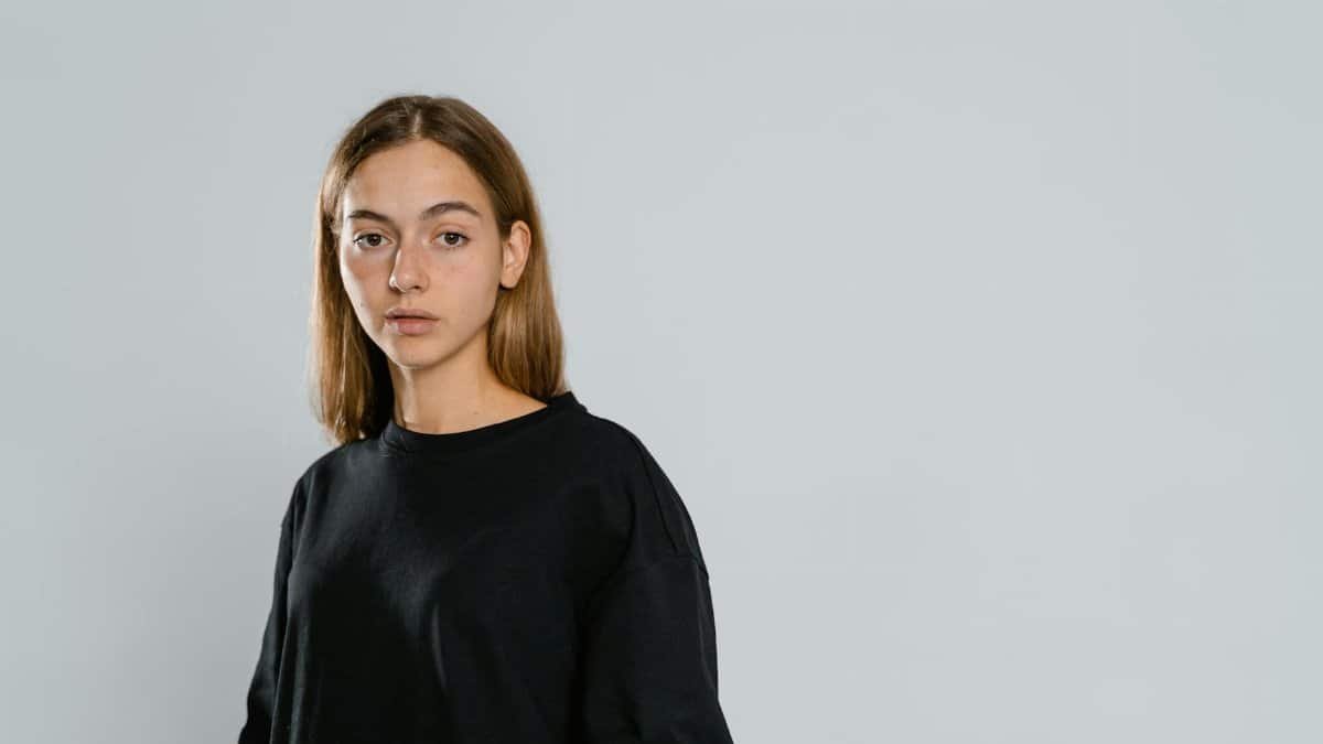 Teen girl with long brown hair posing in black t-shirt, offering copy space.