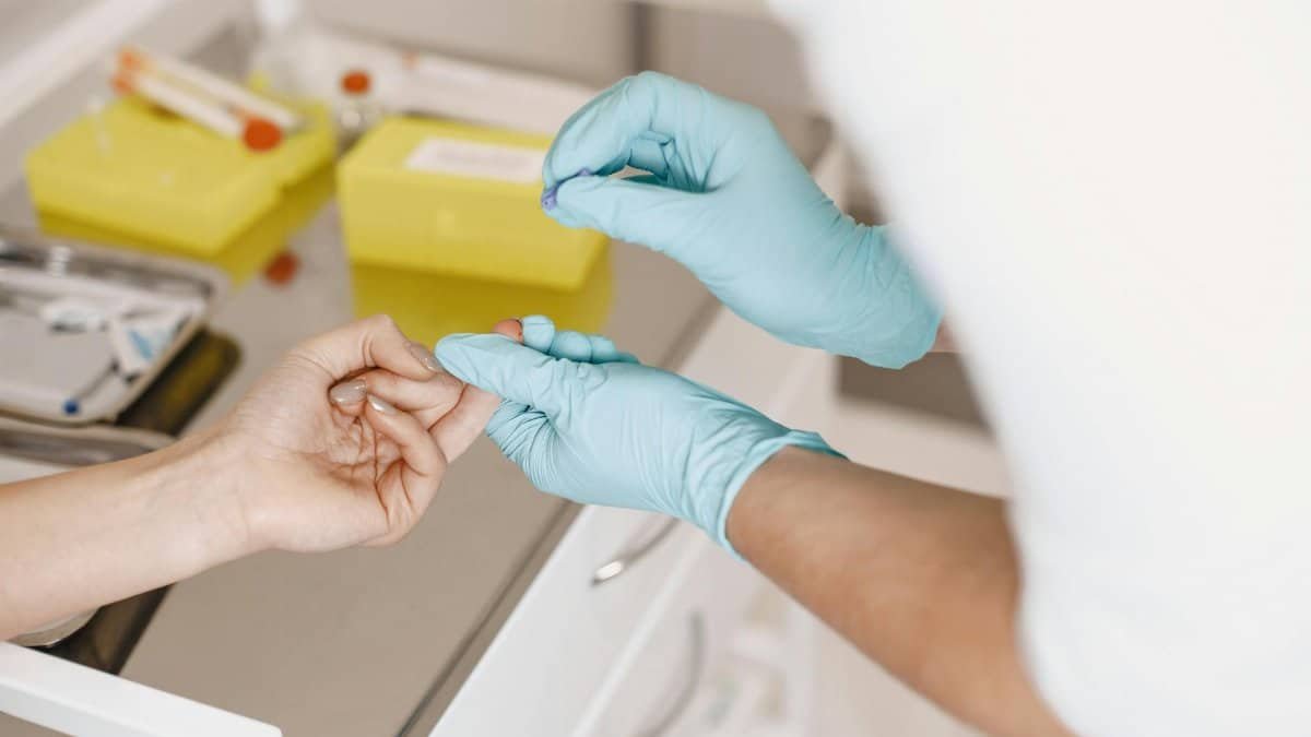 A healthcare professional wearing gloves takes a blood sample from a patient. Medical setting.