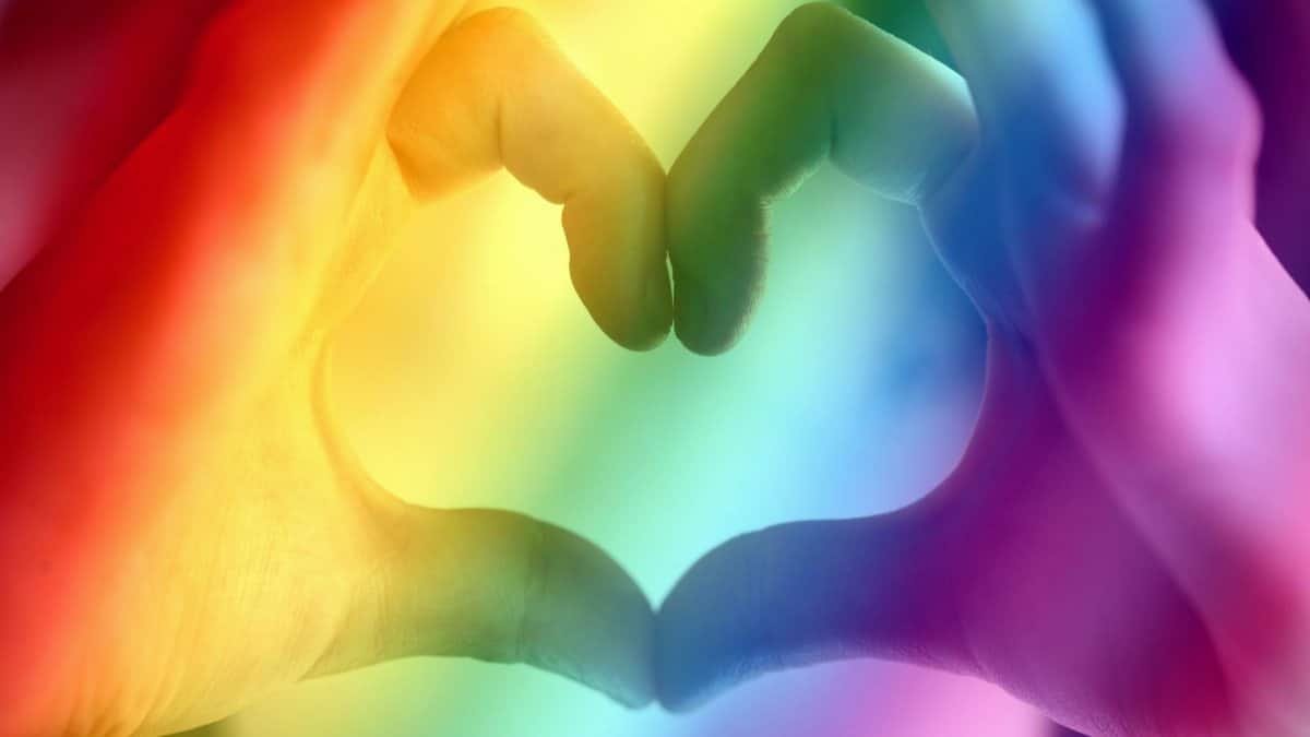 Hands forming a rainbow heart shape, symbolizing love, unity, and LGBTQ pride.