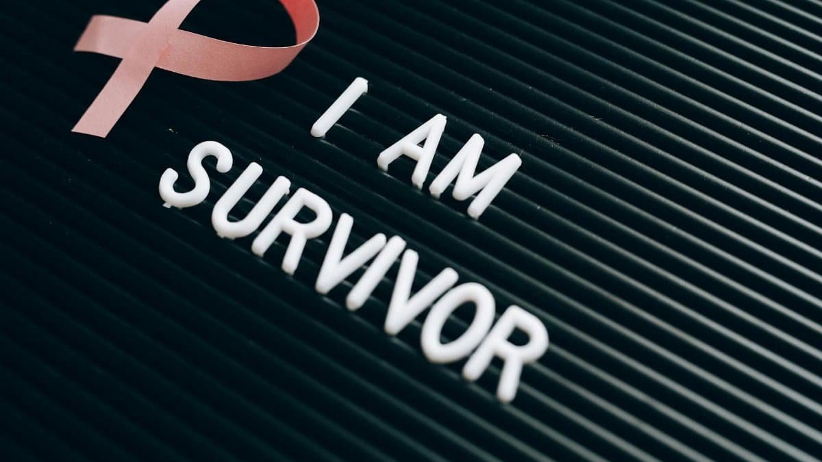 Breast cancer survivor message with pink ribbon and empowering text on board.