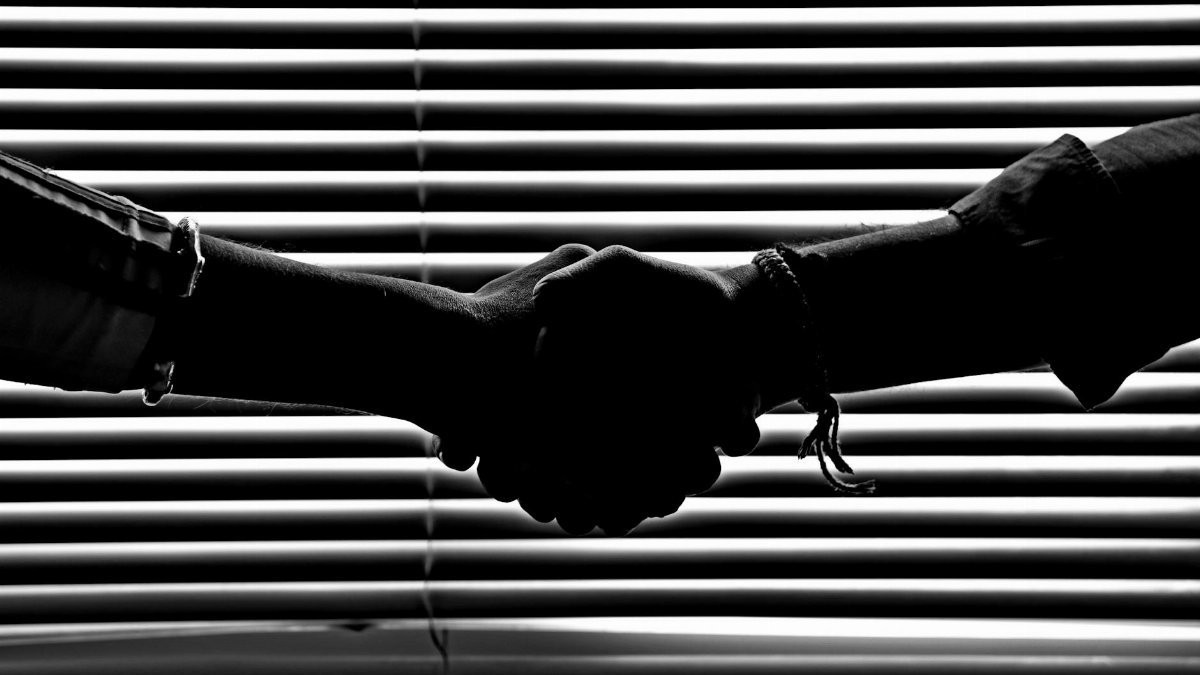 Silhouette of two people shaking hands symbolizing partnership and trust.