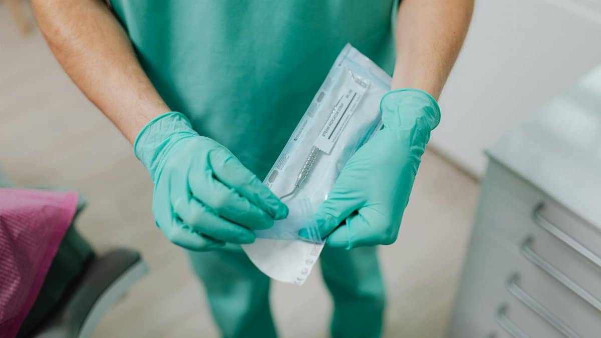 Close-up of a dental professional unpacking sterile instruments in a clinic.