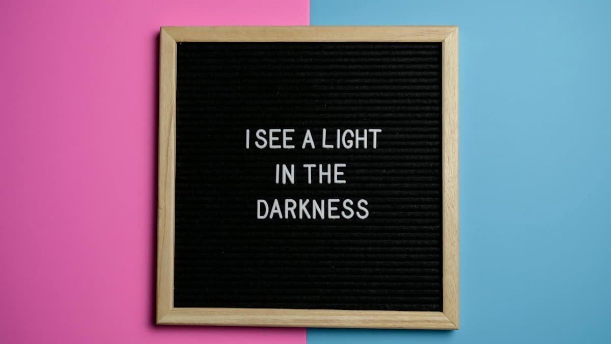 Motivational quote on a black letterboard with a pink and blue background.