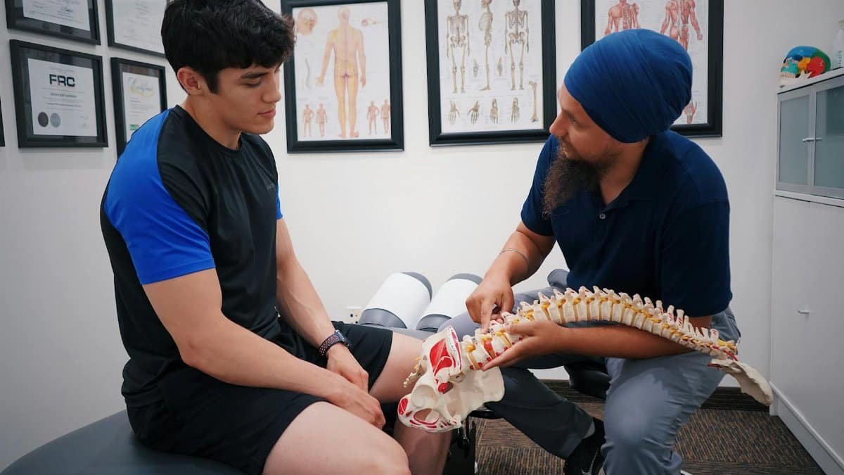 A doctor explains spinal issues to a patient using a spine model during a medical consultation.