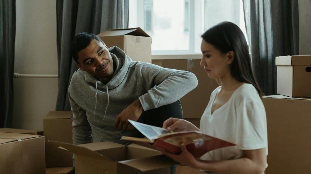 A couple exploring their new home while unpacking boxes and looking at a photo album.