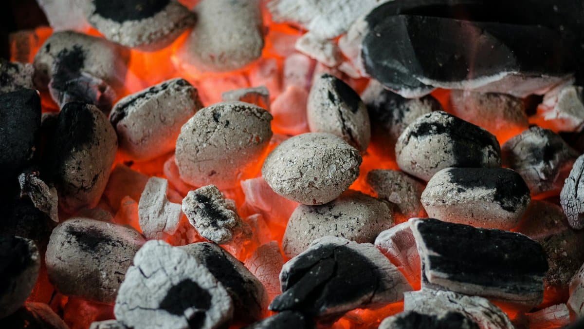 Close-up of glowing charcoal briquettes ready for outdoor barbecue grilling.