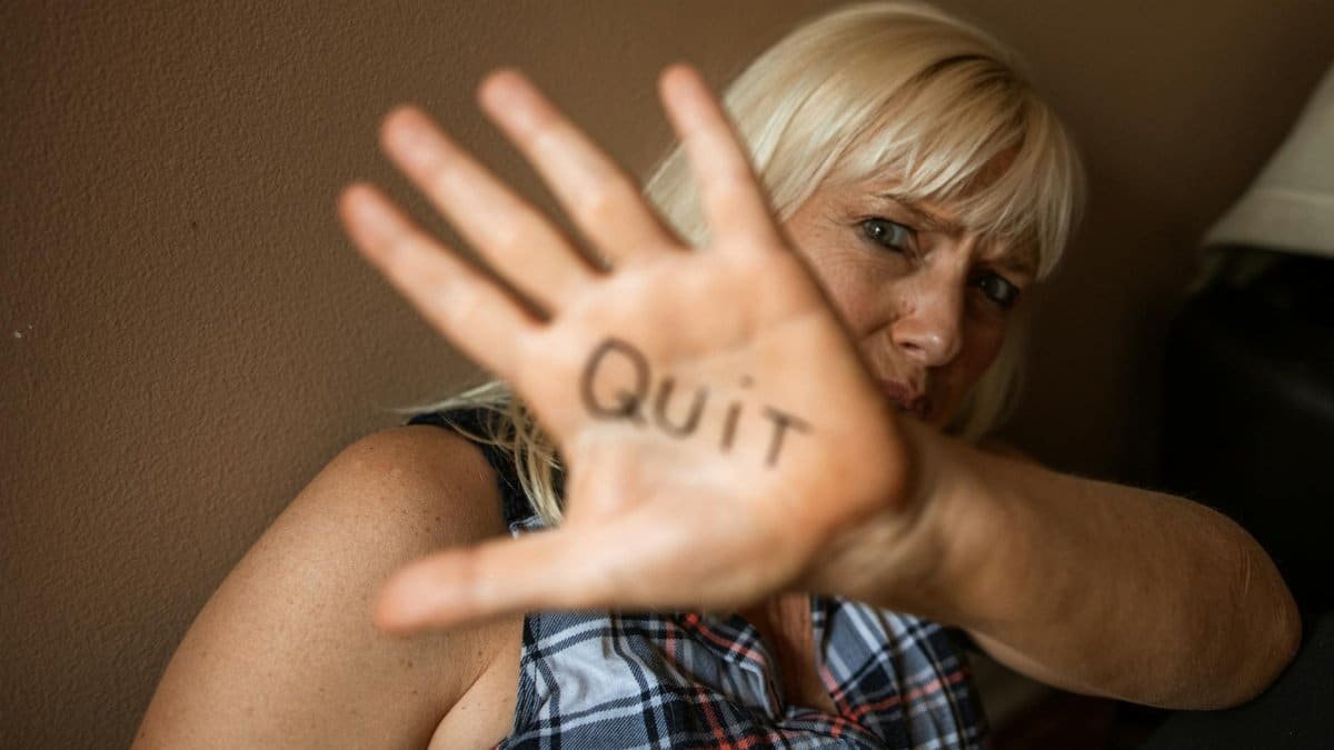 A powerful portrayal of a woman displaying 'Quit' on her palm, emphasizing resilience and advocacy.