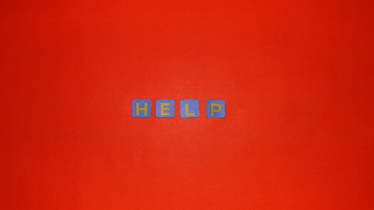 Minimalist image showing 'HELP' spelled out on a vibrant red backdrop.