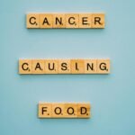 Conceptual image showing words 'cancer causing food' on Scrabble tiles against a blue background.