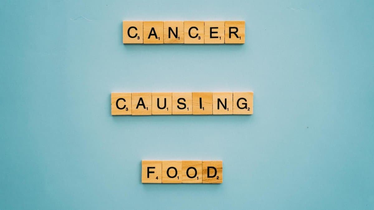 Conceptual image showing words 'cancer causing food' on Scrabble tiles against a blue background.