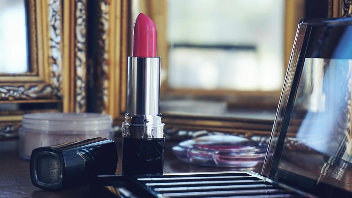 Elegant close-up of pink lipstick on a stylish makeup vanity with reflections.