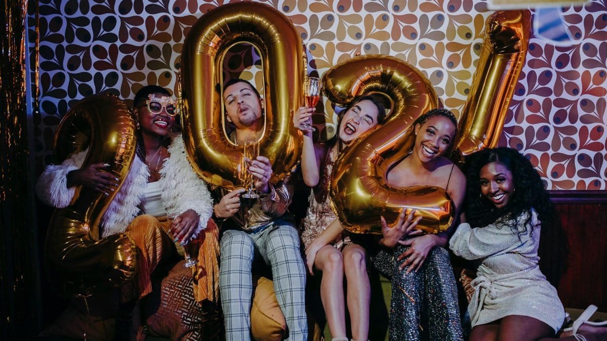 A group of diverse friends celebrating New Year's Eve with balloons and champagne, embodying joy and togetherness.
